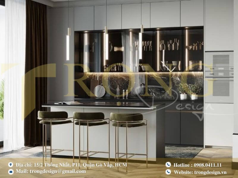 Bếp hiện đại tông xám trầm với đảo bếp liền bàn ăn và tủ kính trưng bày có đèn.