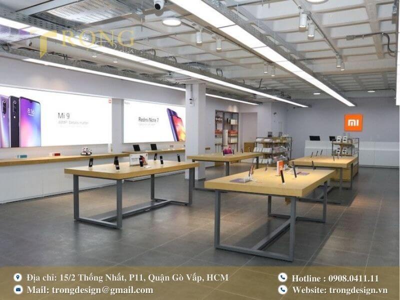Cửa hàng với không gian mở, bàn trưng bày gỗ và biển quảng cáo kỹ thuật số